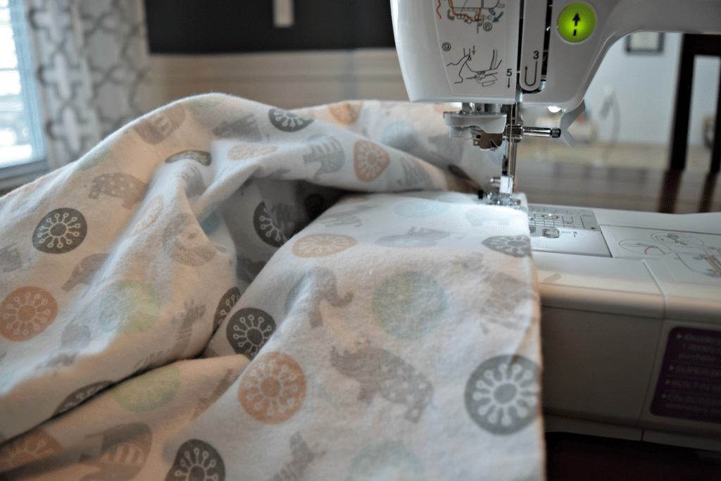 This adorable baby animal fabric is being sewed into a homemade baby blanket