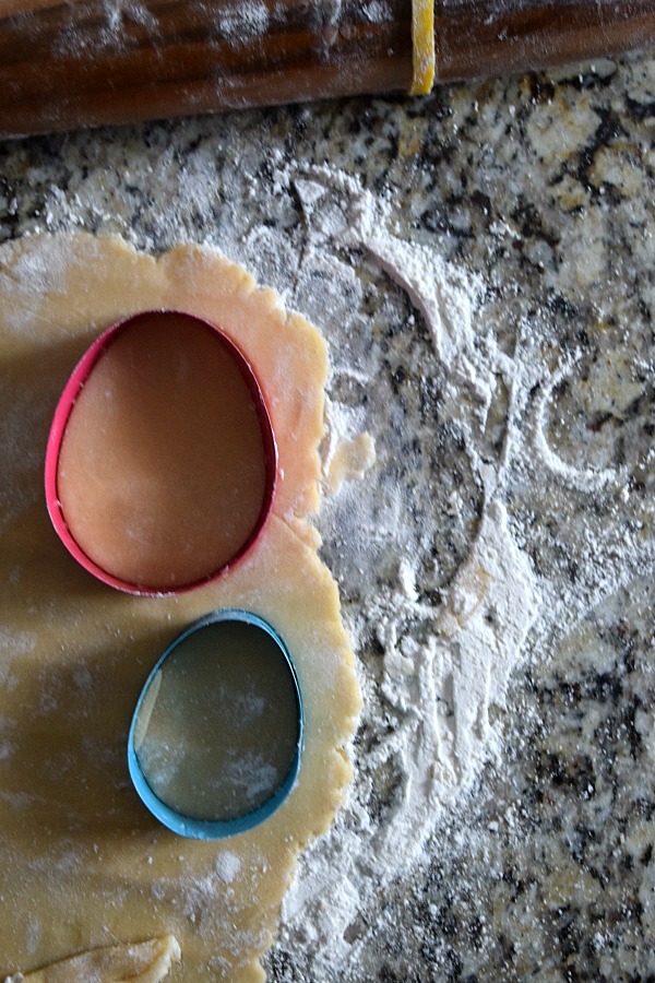 Roll the sugar cookie dough out on a floured surface and cut out Easter egg shapes with cookie cutters