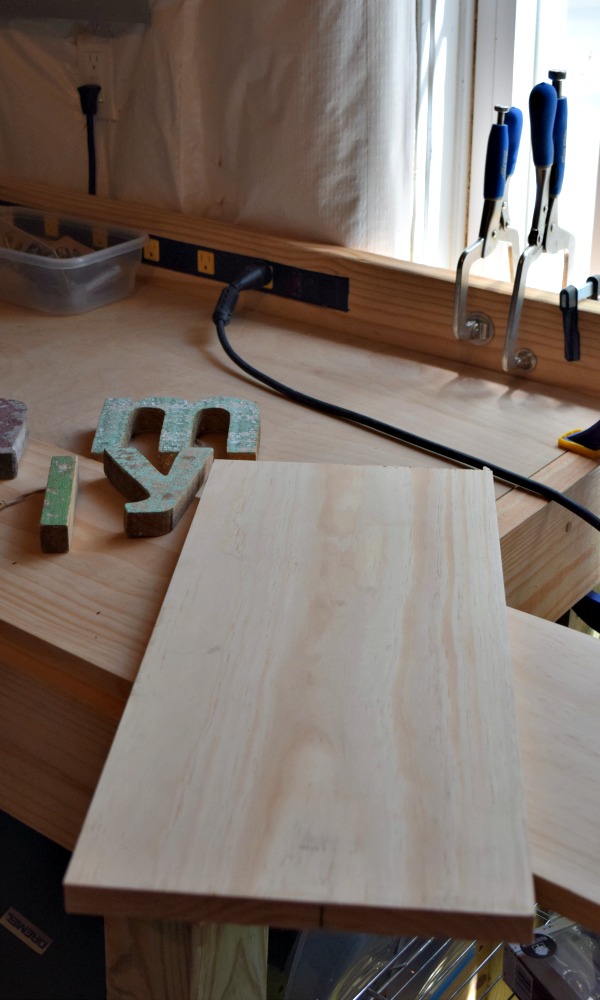 Start by cutting a wood board to the right size to fit all the letters for your DIY sign