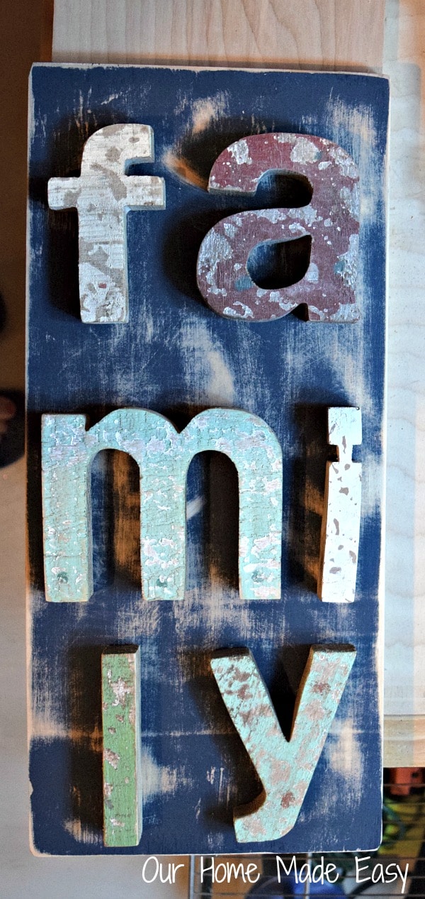 Wood letters that spell out "family" are arranged on the weathered board