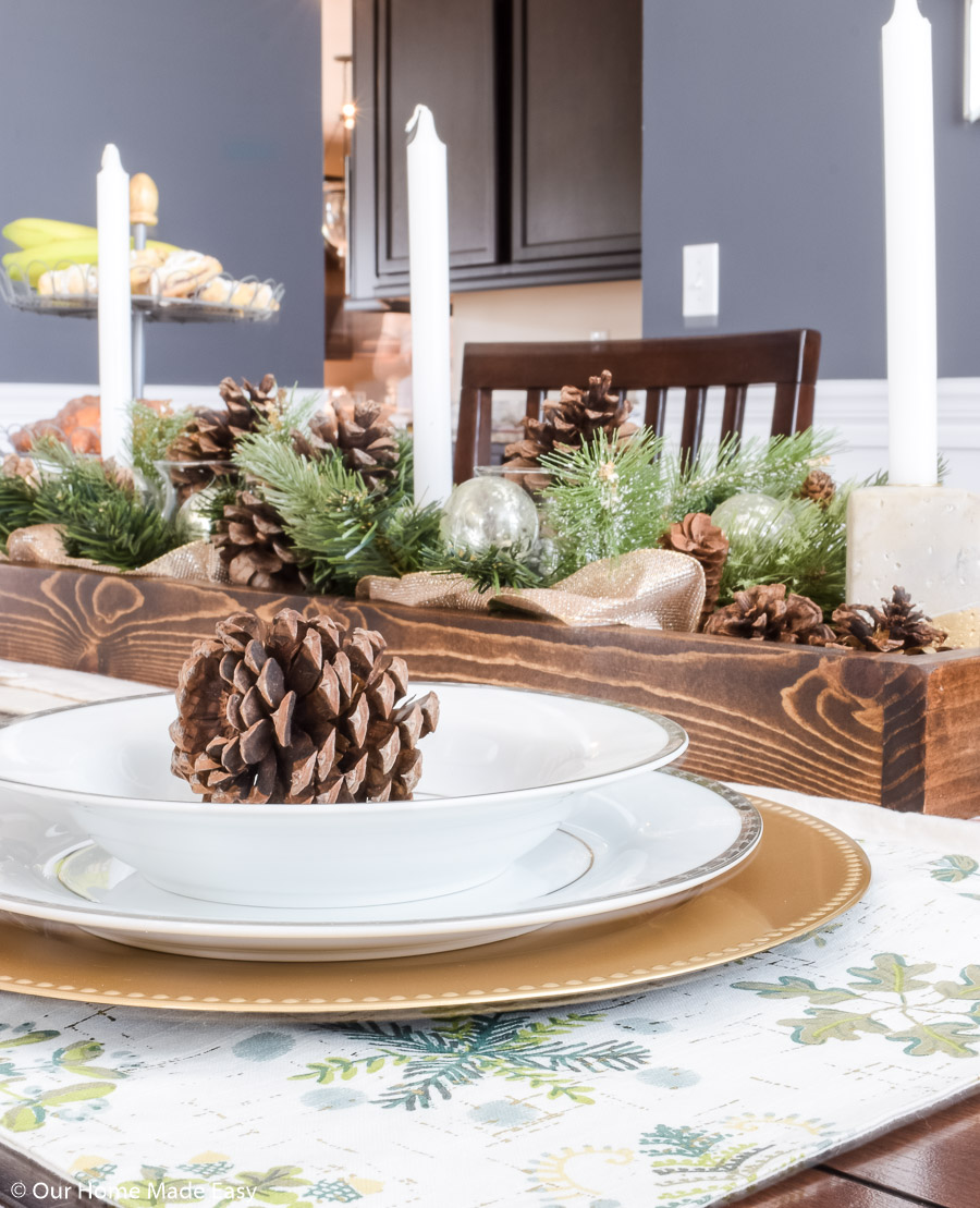 Our Christmas dining room table centerpiece is a simple DIY wood box filled with pinecones and faux fir tree branches