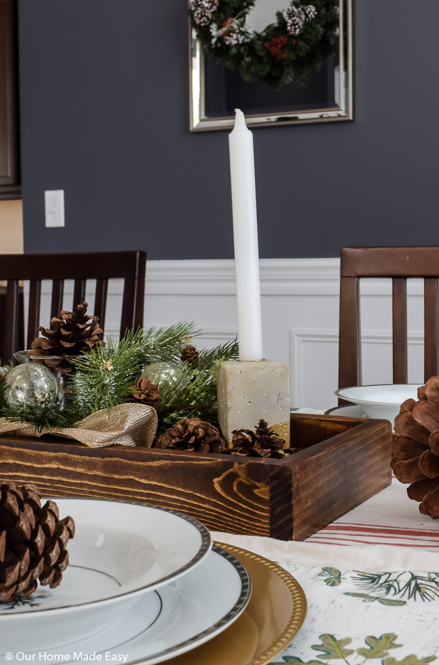 Our dining room table Christmas centerpiece has candlesticks, pinecones, and faux fir branches