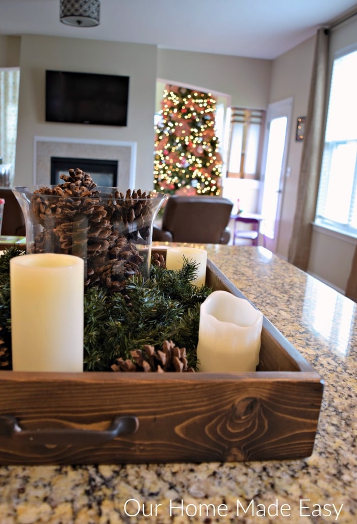 The view from our kitchen--a festive pinecone and candle centerpiece with a glowing Christmas tree in the background