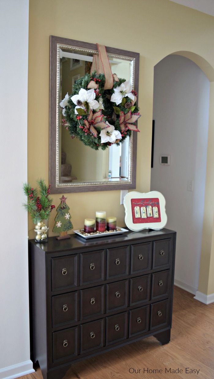 Our foyer is decorated with cozy Christmas decor, including a poinsettia wreath 