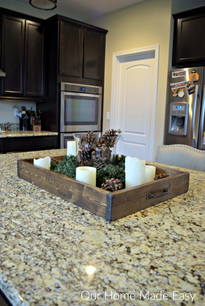 For some cozy Christmas decor in our kitchen, we filled this wood serving tray with some pinecones and candles