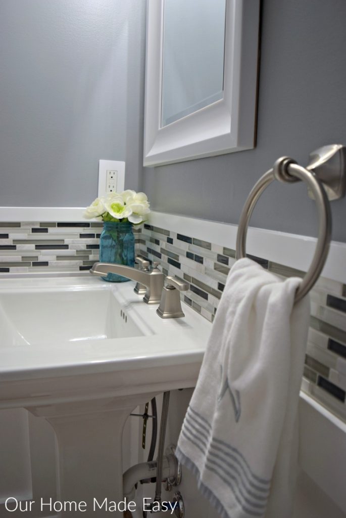 Black, white, and gray tile backsplash with gray walls and a white pedestal sink in our new powder room