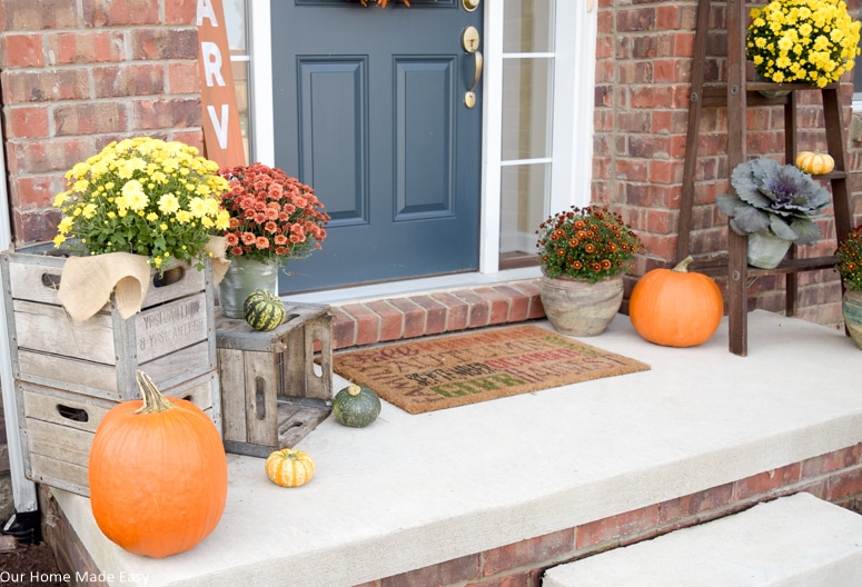 Our fall front porch has large pumpkins, bright potted mums, and adorable mini pumpkins