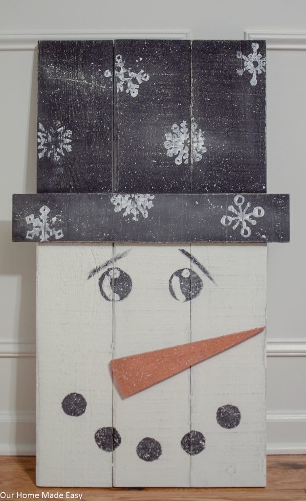 Make this super easy pallet snowman! Use some leftover paint and wood to build this easy DIY snowman. No fancy tools needed!