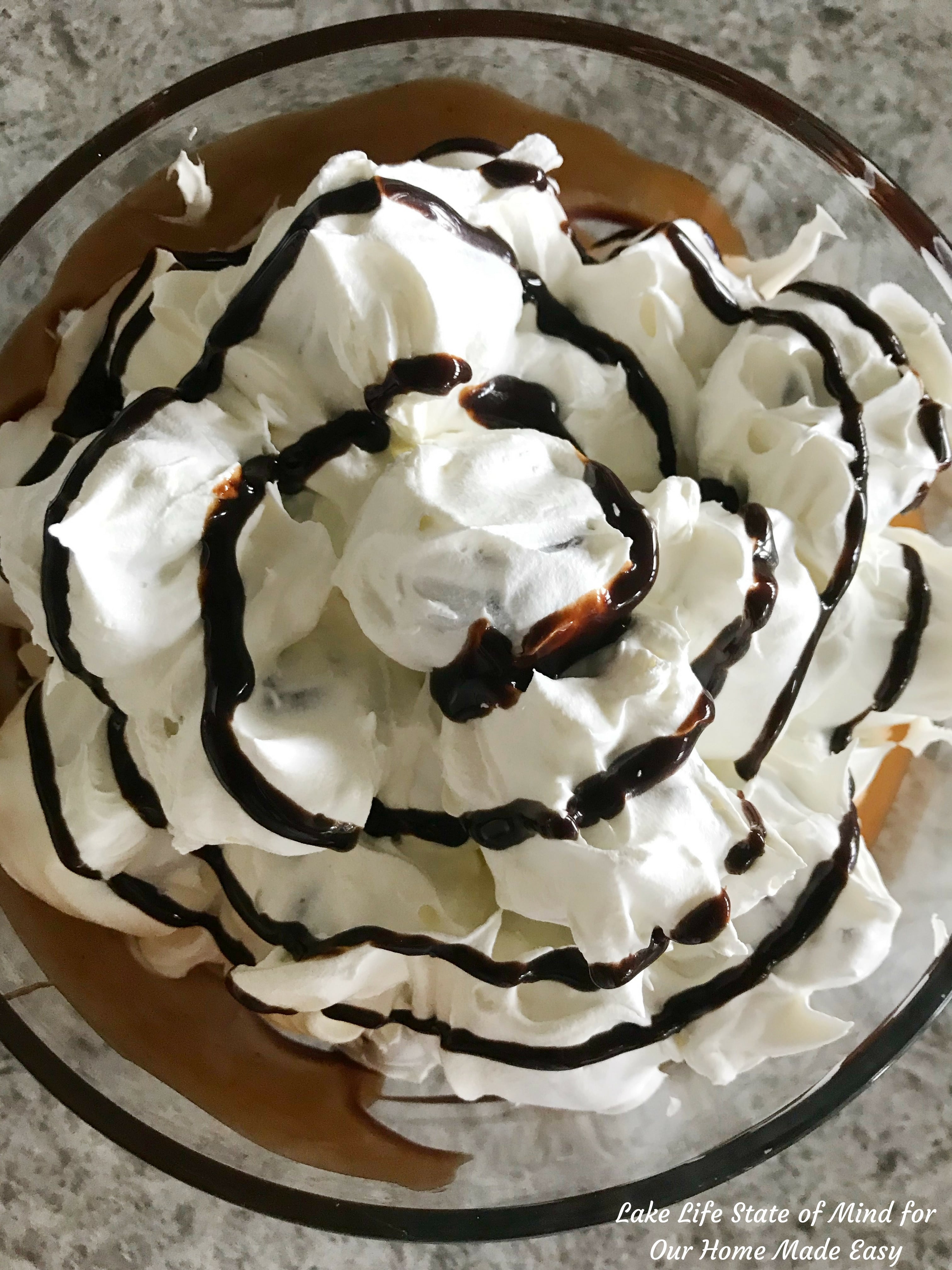 Decadent chocolate syrup drizzled over whipped cream covered cream puffs