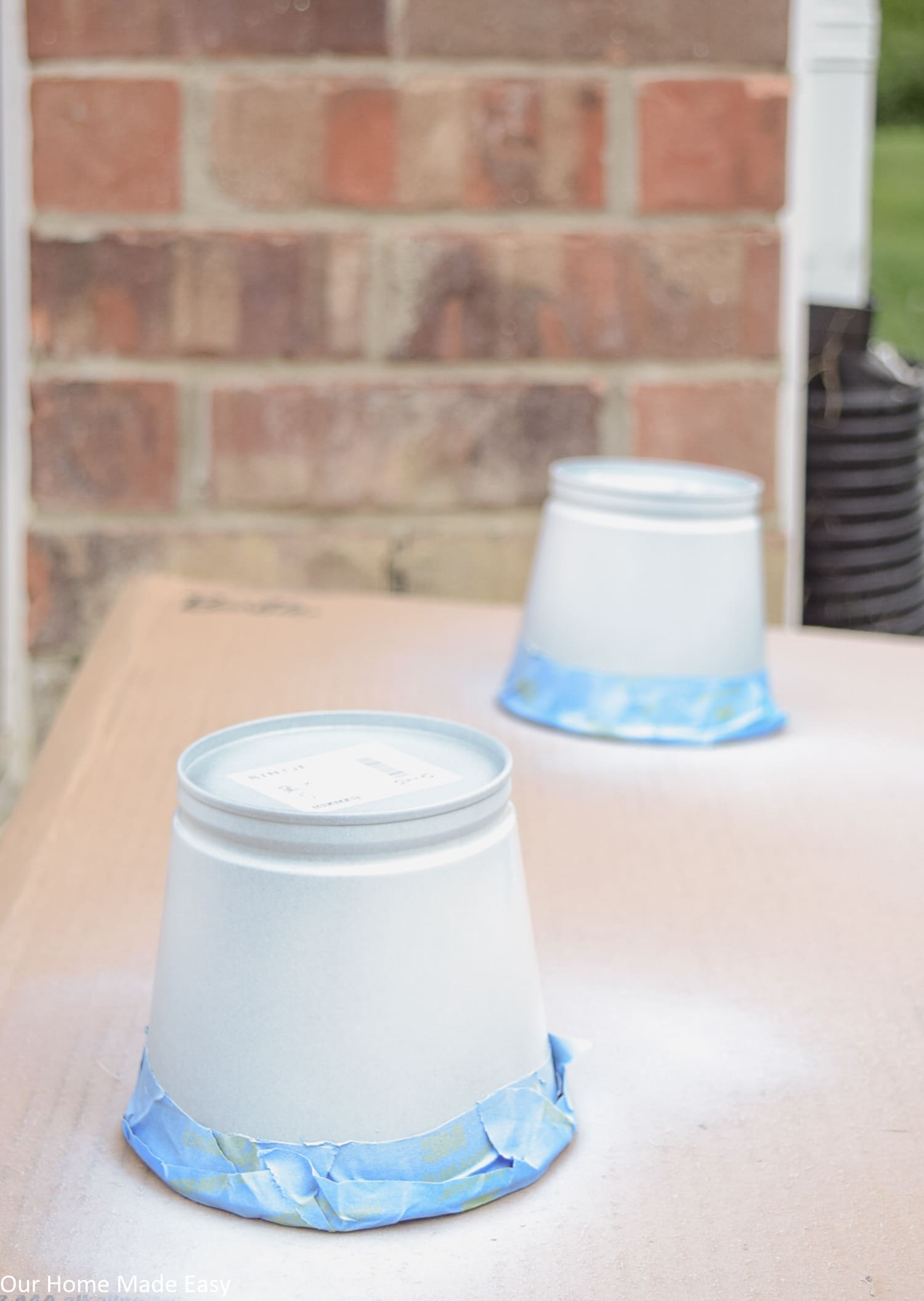 These metal planters receive their first coat of white Plasti Dip crafting spray paint