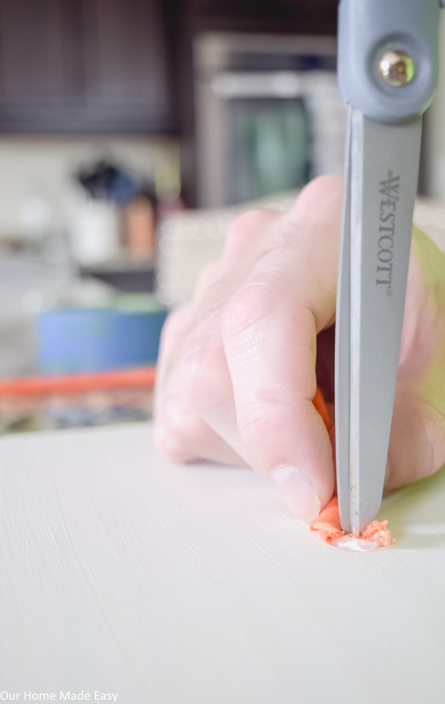 Use a scissors and some hot glue to secure the end of the fabric to the wood board