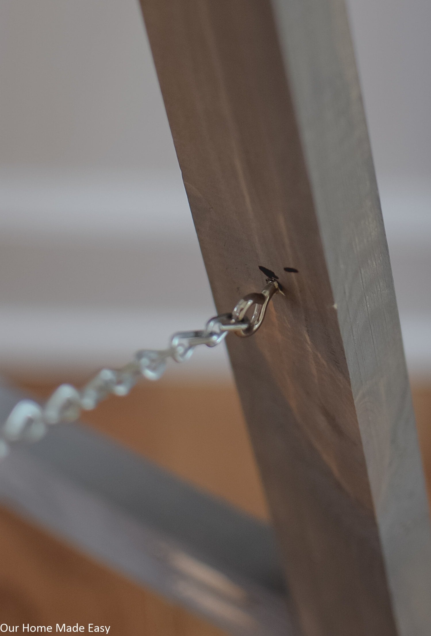 A close up look at the eye hooks and chains on the support legs of this DIY wooden Fall sign
