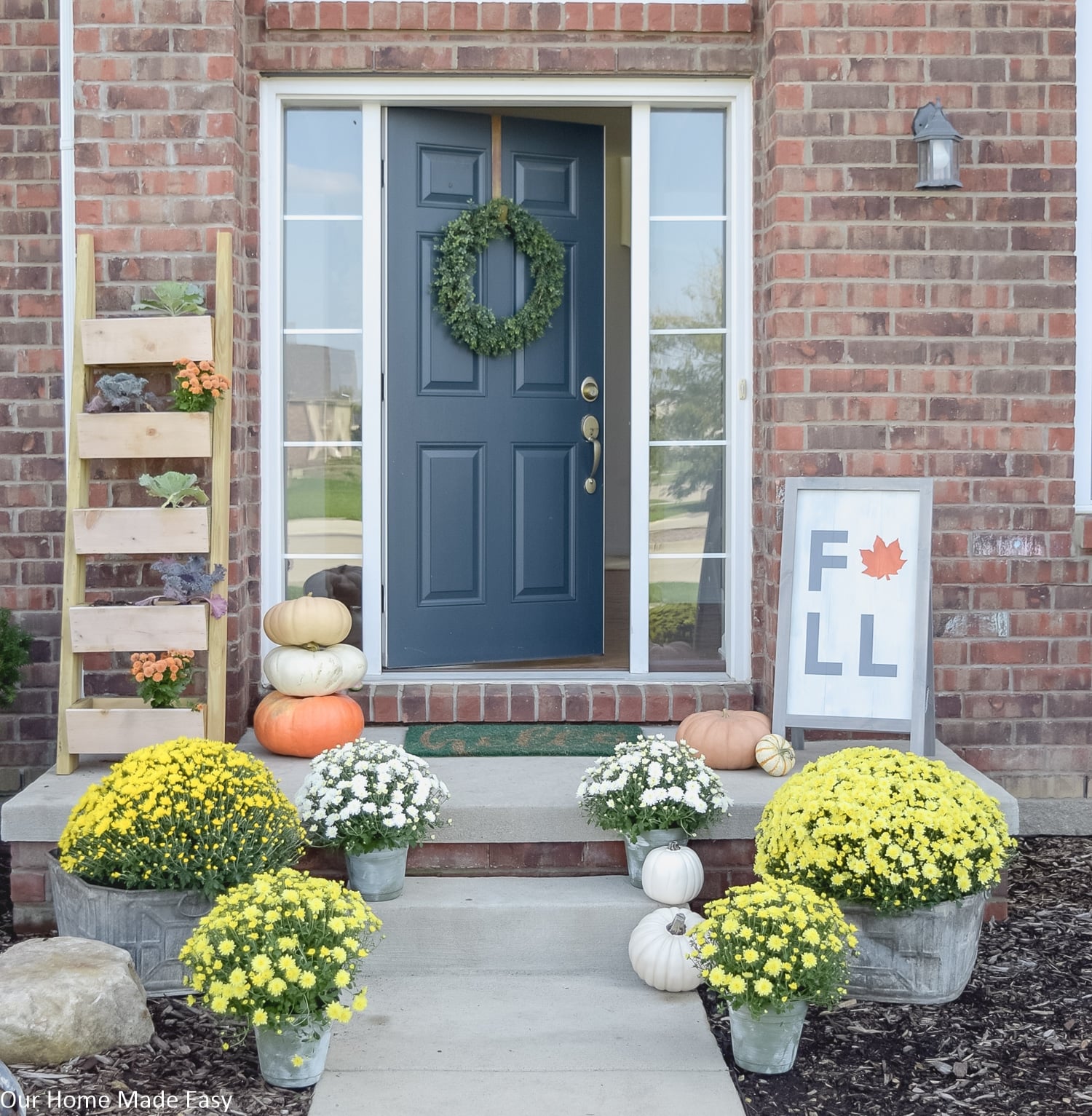 this inviting fall front porch is decorated with arrangements of bright colored mums