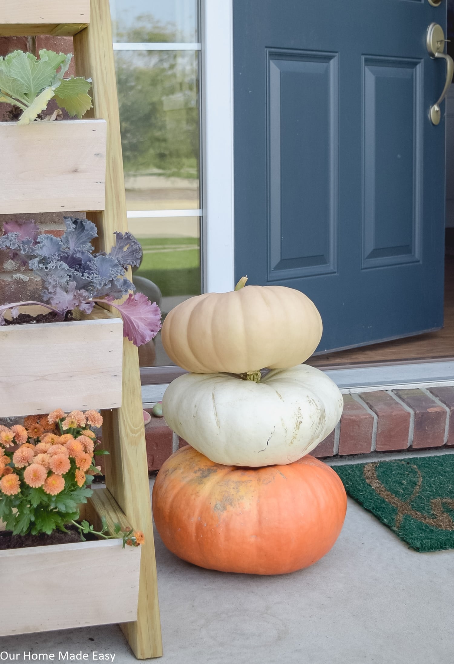 this simple fall front porch has small accents like pots of mums and harvest pumpkins