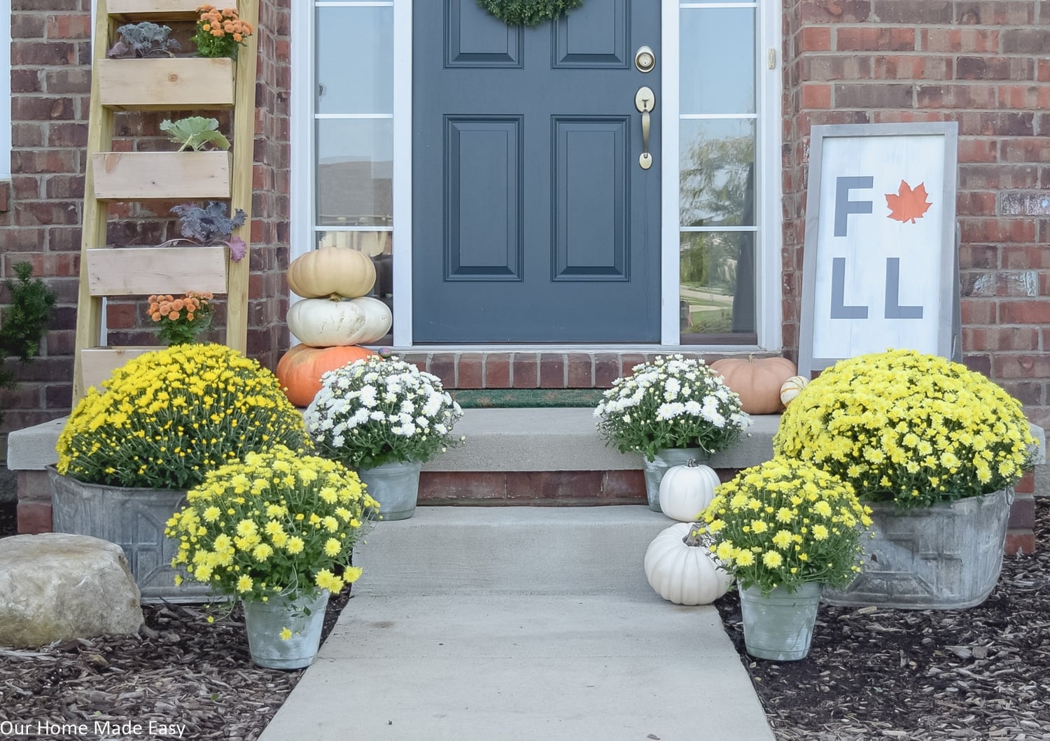 this fall themed front porch is warm and inviting with potted mums and harvest pumpkins