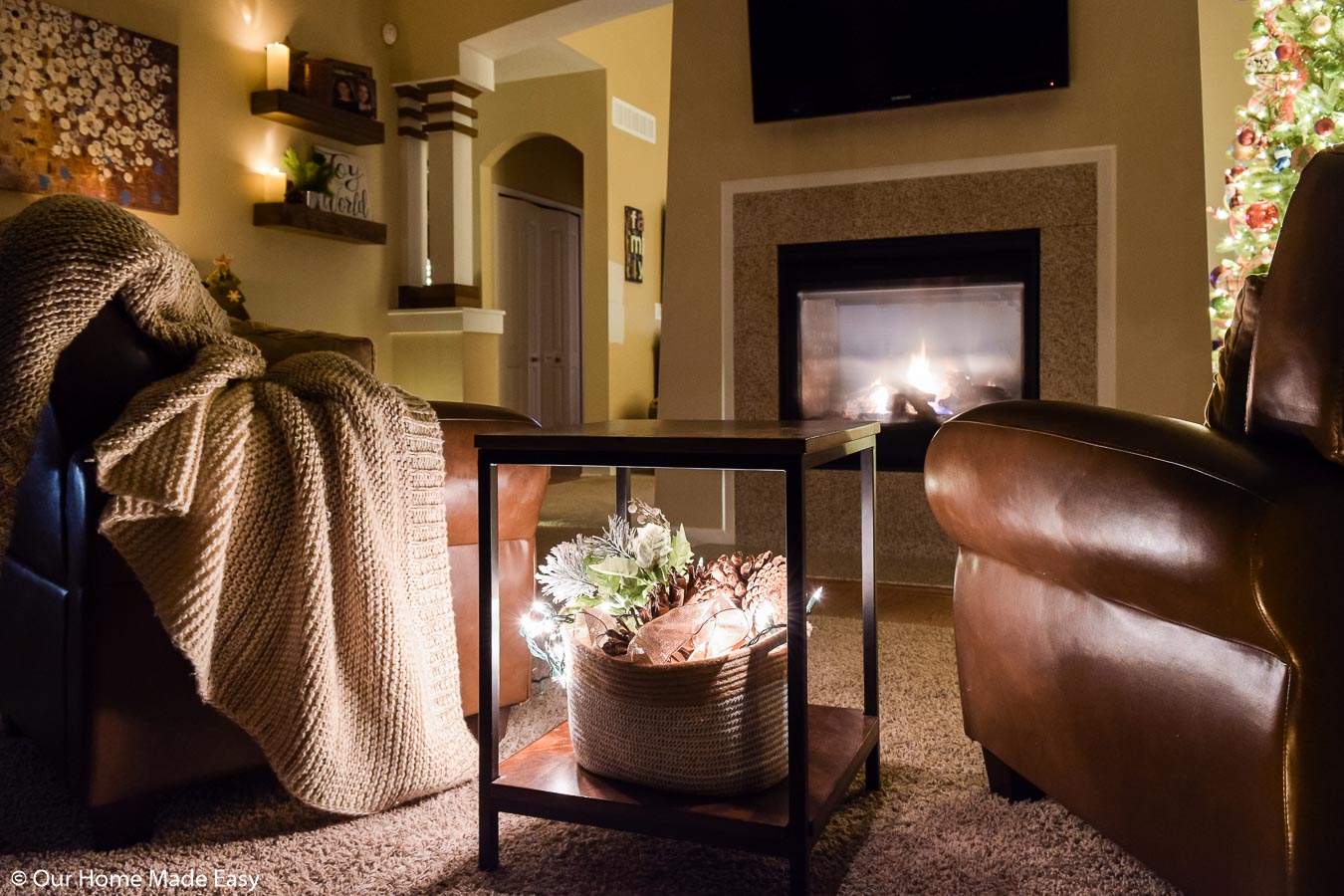 This simple side table decor is a wicker basket with pinecones and fir tree branches with tucked-in Christmas lights