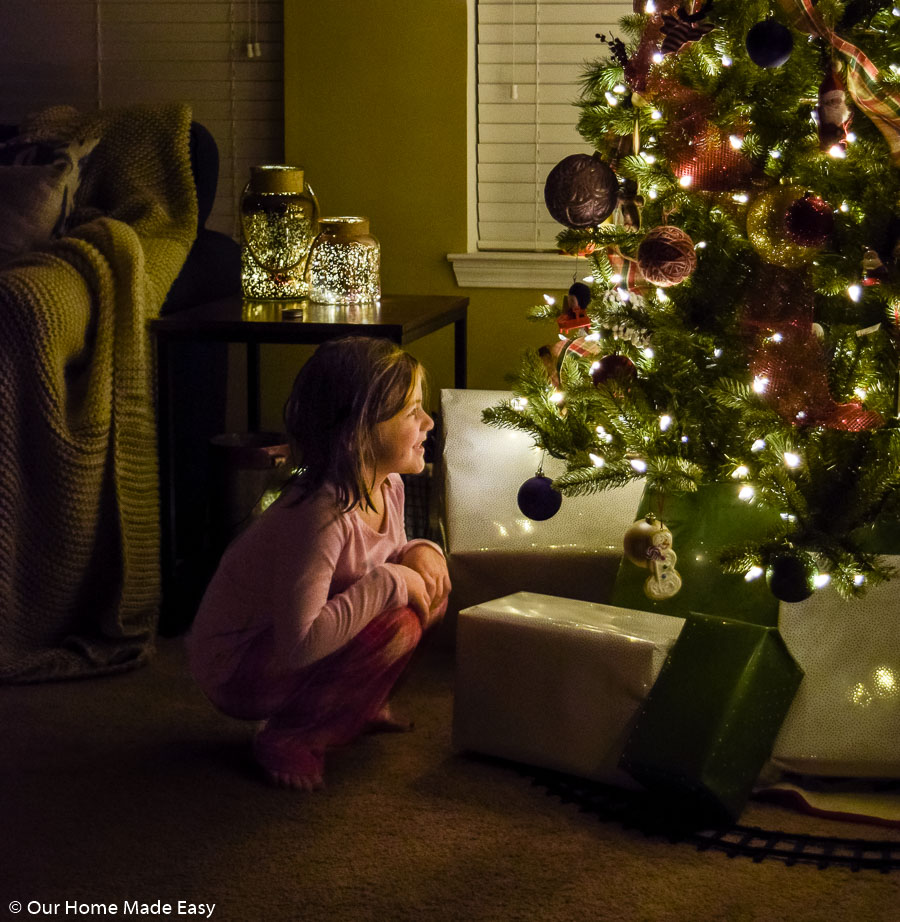 My youngest daughter, Aubrey, crouched in front of our living room Christmas tree, admiring the lights, ornaments, and presents