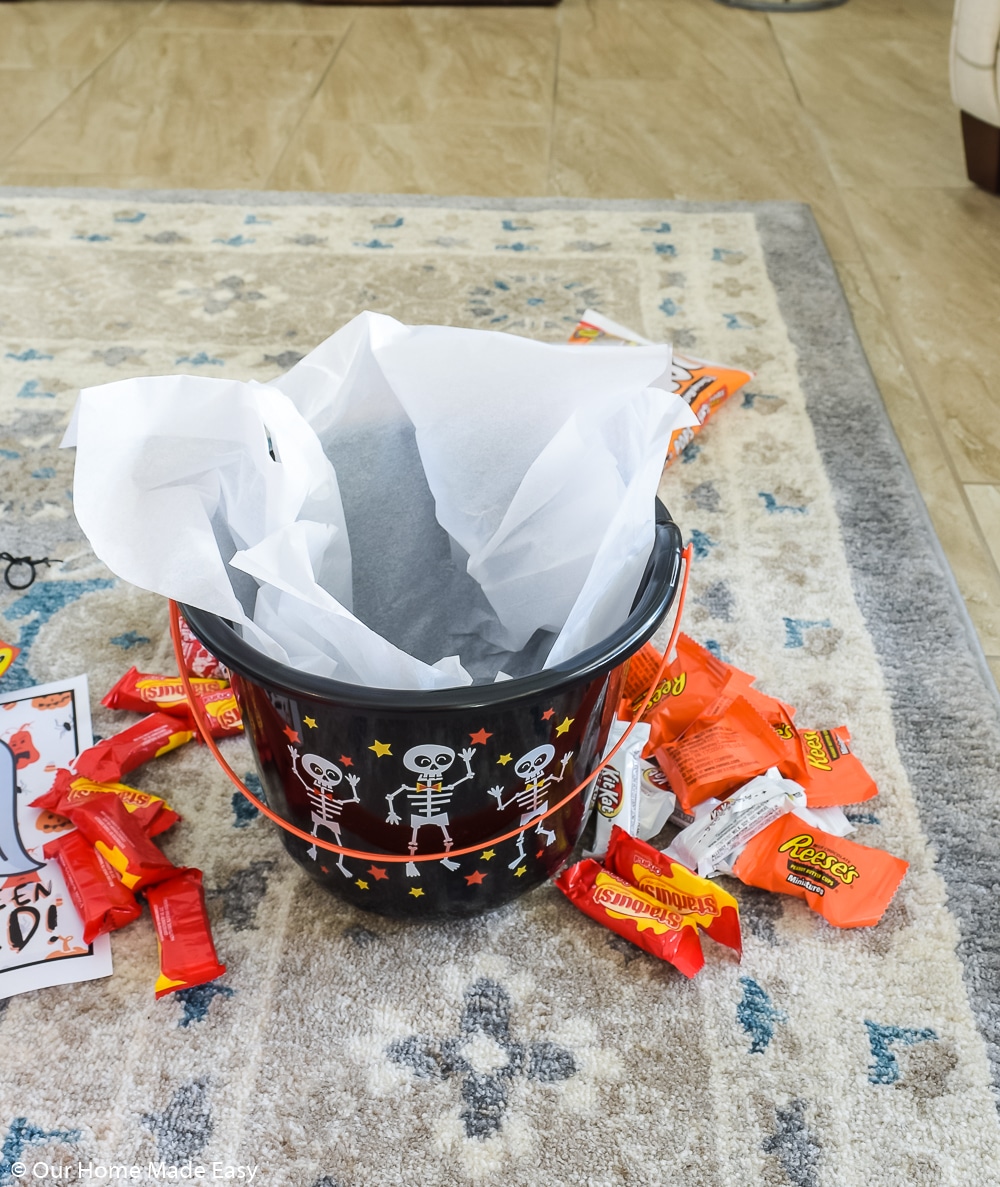 To make a You've Been Booed bucket, all you need is a Halloween bucket, candy, and some tissue paper.