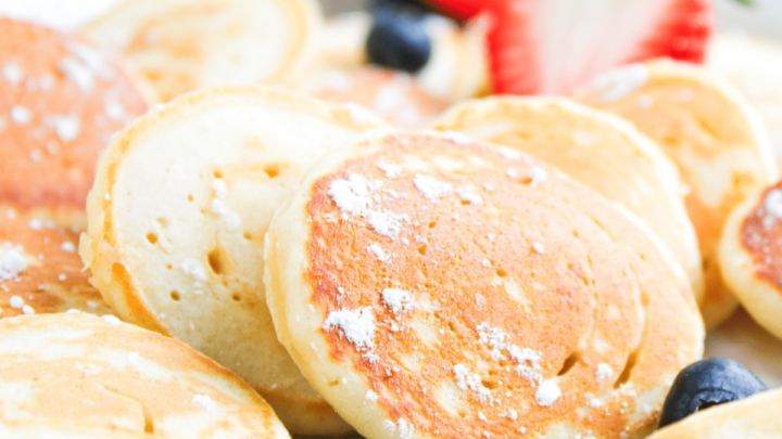 Stack of mini pancakes on plate with fresh fruit