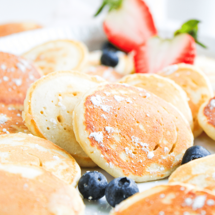 Stack of mini pancakes on plate with fresh fruit