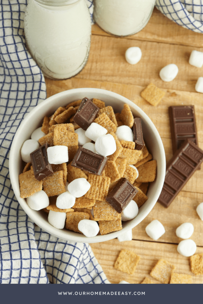 Smores snack mix finished in bowl with wood background and blue cloth