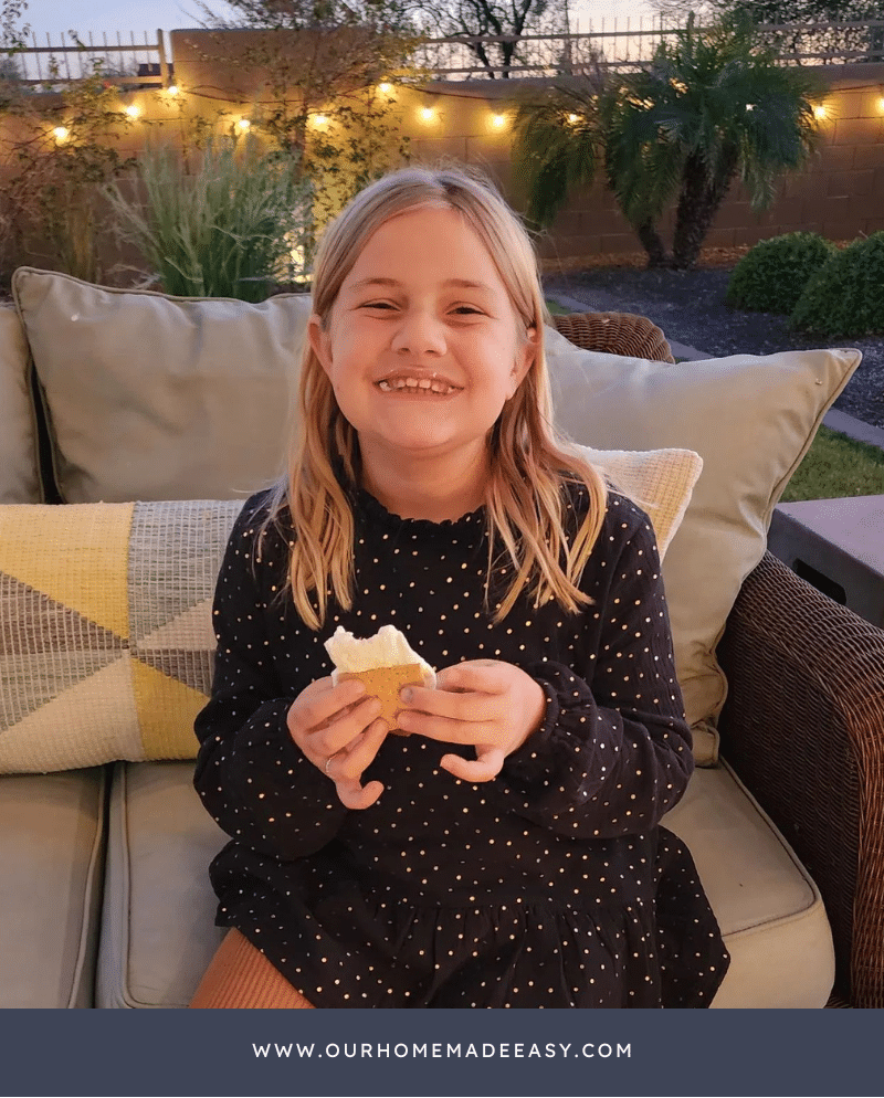 young girl enjoying a smore by campfire