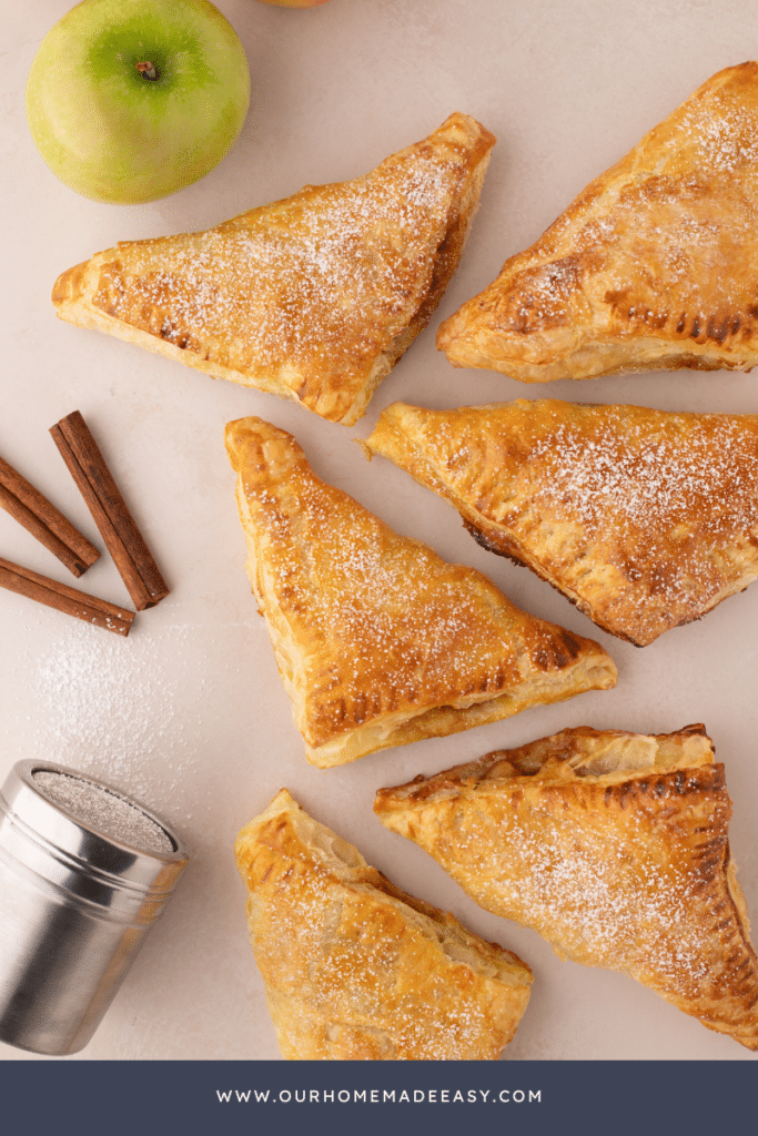 finished apple turnovers on countertop with cinnamon sticks