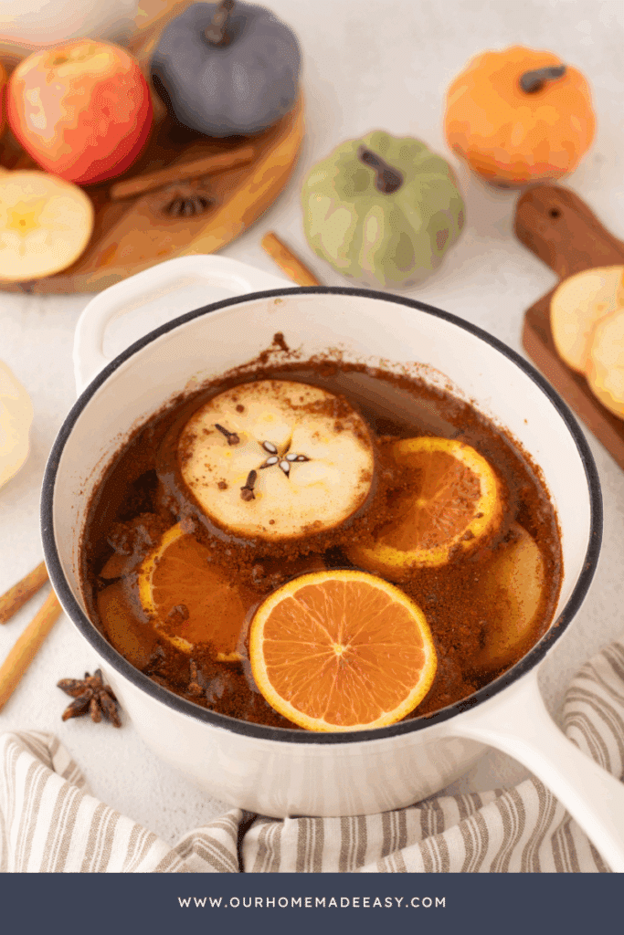white ceramic pot with sliced oranges, apples, and pumpkin spices