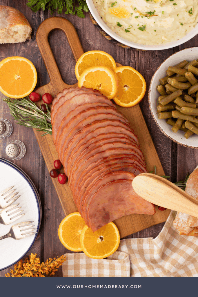 finished holiday baked ham on cutting board with sliced oranges