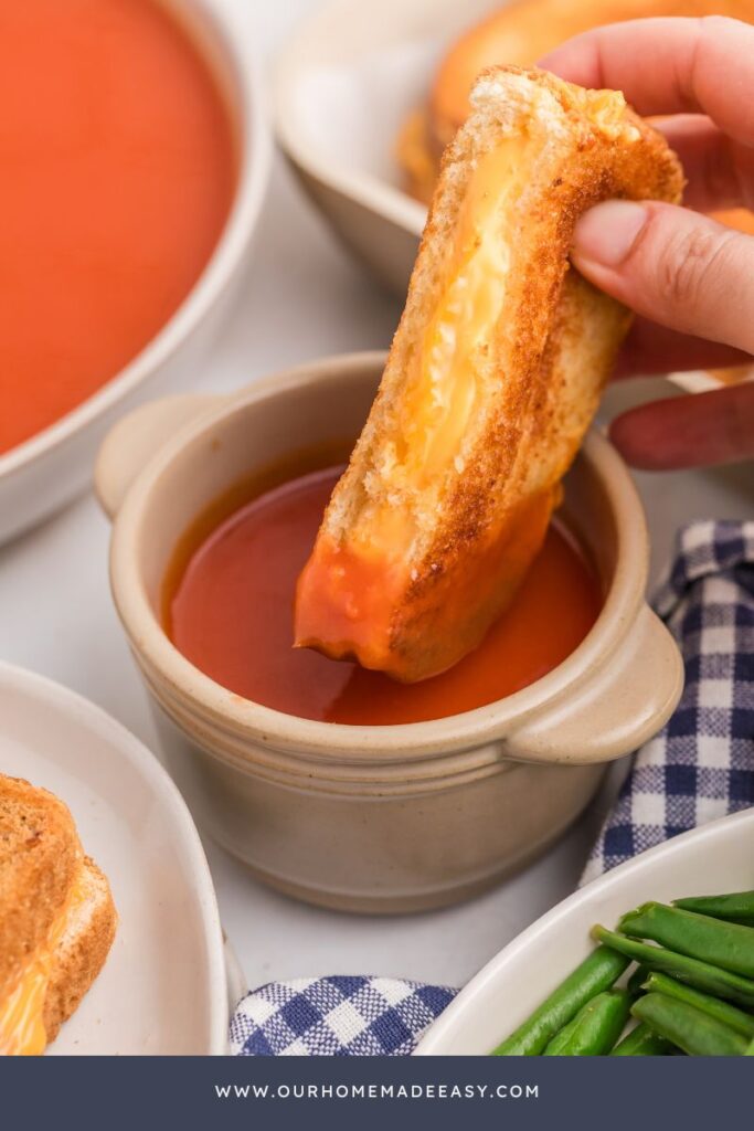 dipping grilled cheese sandwich into tomato soup