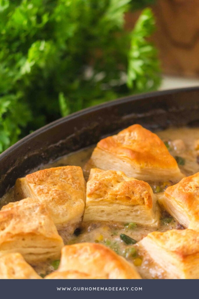 close up of Ground beef pot pie with golden biscuit topping and creamy ground beef and vegetable filling in a skillet.