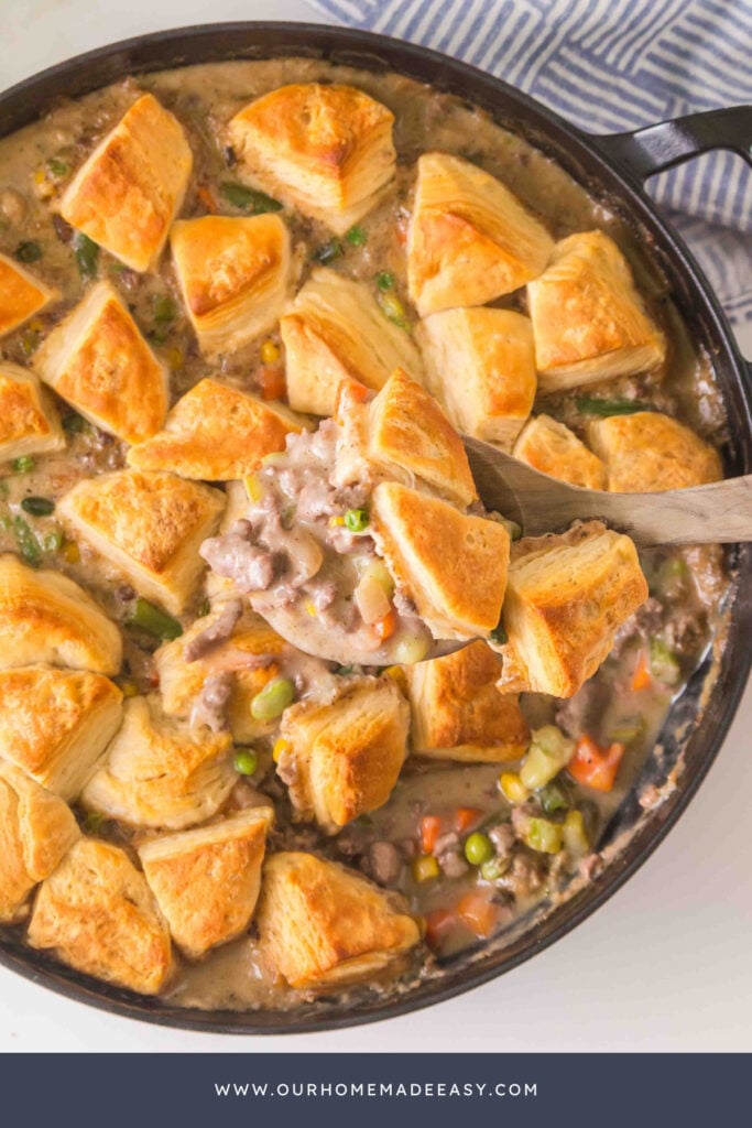 Ground beef pot pie with golden biscuit topping and creamy ground beef and vegetable filling in a skillet.